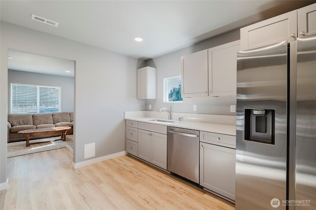 kitchen with visible vents, light wood-style flooring, a sink, stainless steel appliances, and a wealth of natural light