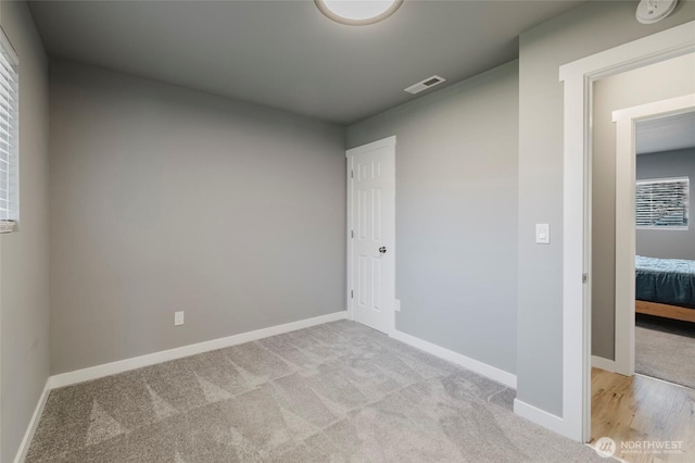 unfurnished room with light colored carpet, visible vents, and baseboards