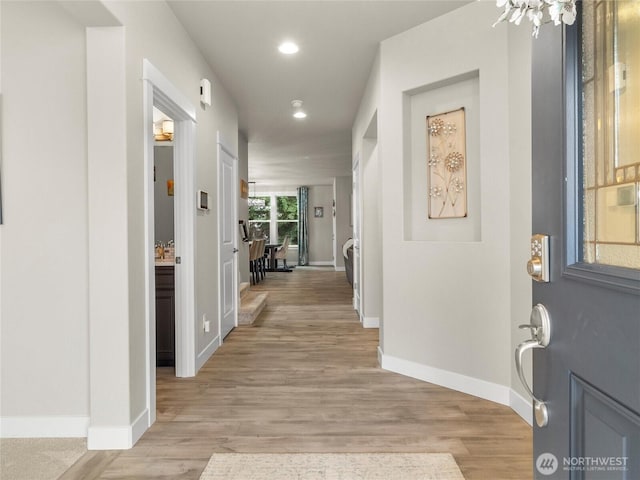 hallway with light wood finished floors, baseboards, and recessed lighting