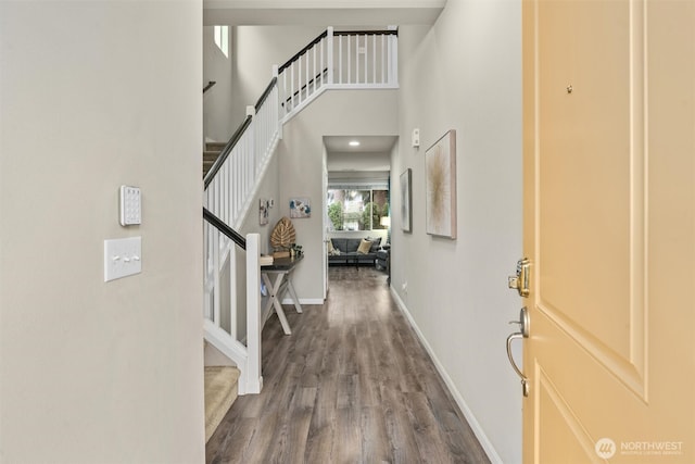 foyer entrance featuring stairs, a high ceiling, wood finished floors, and baseboards