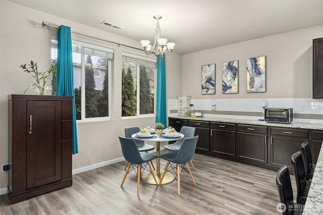 dining space with a chandelier, a toaster, visible vents, baseboards, and light wood-type flooring