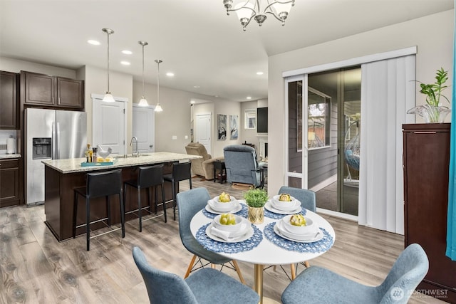 dining room with light wood-type flooring, a chandelier, and recessed lighting