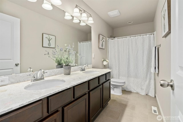 bathroom featuring toilet, double vanity, visible vents, and a sink