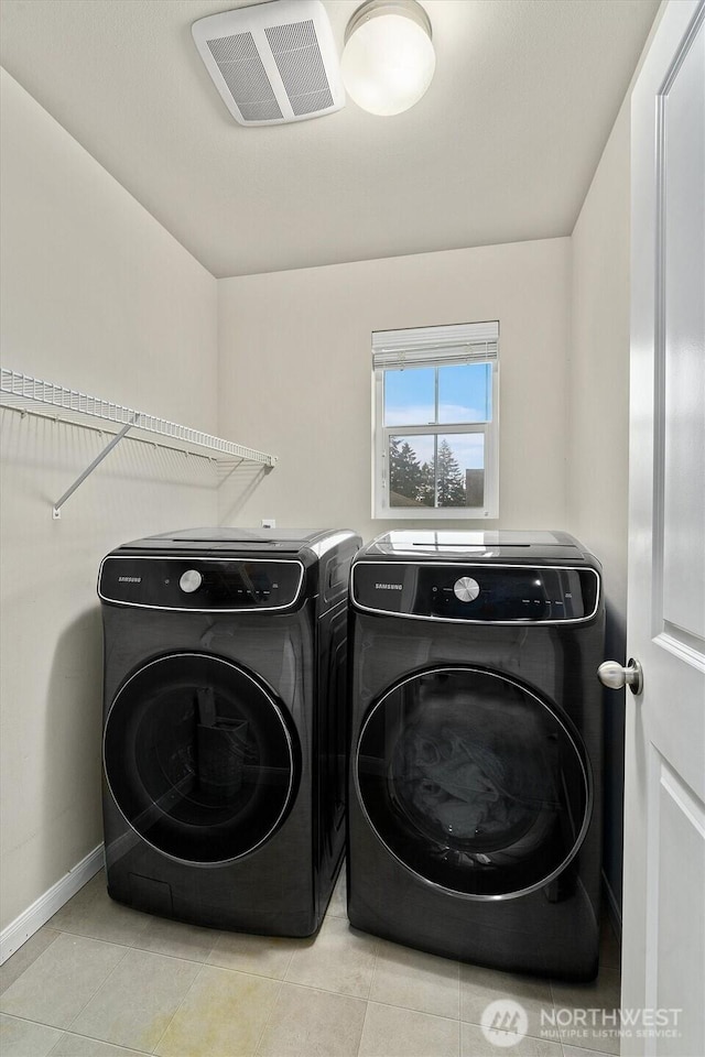 laundry room featuring laundry area, tile patterned flooring, washing machine and clothes dryer, and visible vents