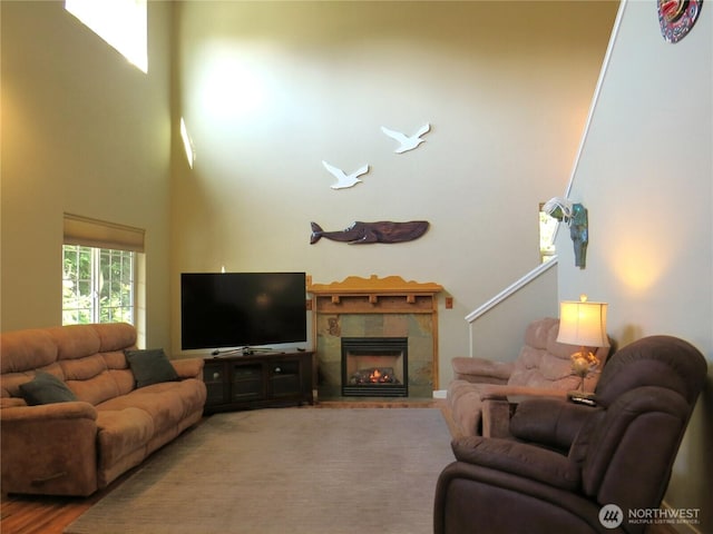 living room featuring a high ceiling, wood finished floors, and a tile fireplace