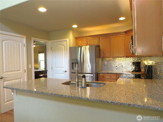 kitchen with brown cabinets, recessed lighting, stainless steel appliances, dark stone counters, and decorative backsplash