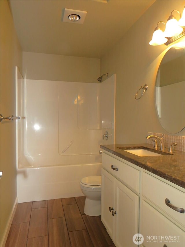 bathroom with wood tiled floor, shower / bathing tub combination, toilet, and vanity