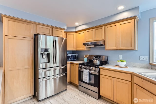 kitchen featuring light countertops, light brown cabinetry, under cabinet range hood, and stainless steel appliances