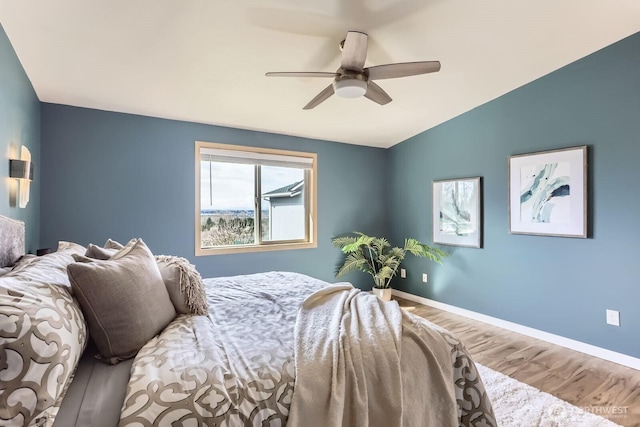 bedroom featuring a ceiling fan, lofted ceiling, baseboards, and wood finished floors