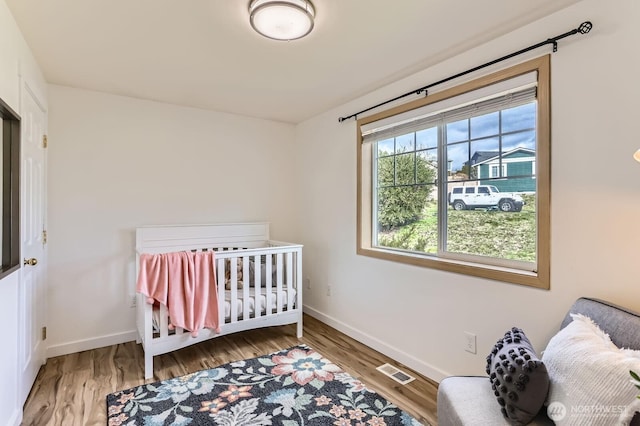 bedroom featuring visible vents, baseboards, and wood finished floors