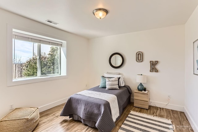 bedroom featuring wood finished floors, visible vents, and baseboards