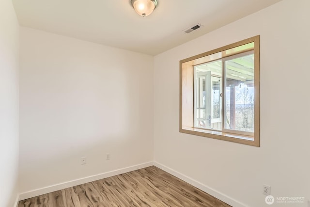 spare room with light wood finished floors, visible vents, and baseboards