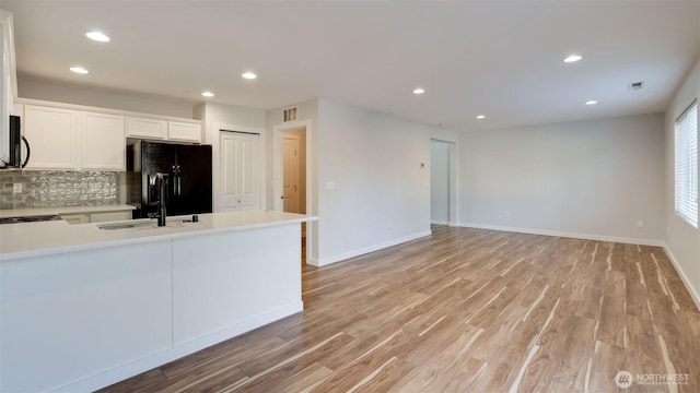 kitchen featuring light wood finished floors, black appliances, backsplash, recessed lighting, and light countertops