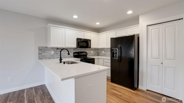 kitchen featuring light wood finished floors, black appliances, light countertops, and a sink