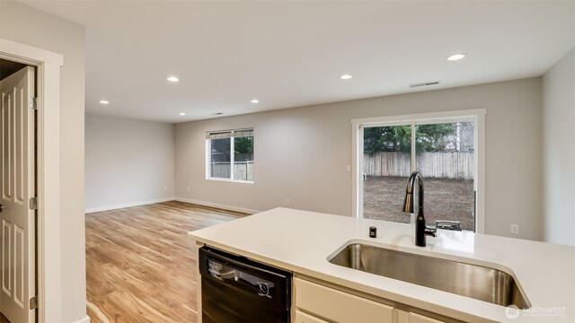 kitchen featuring a wealth of natural light, dishwasher, light countertops, and a sink