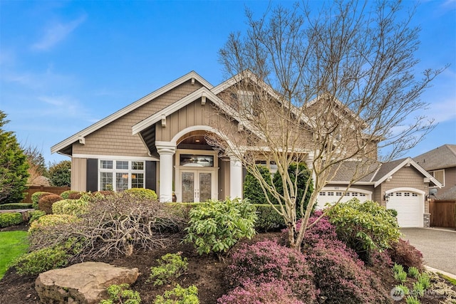 craftsman inspired home with an attached garage, french doors, fence, and driveway