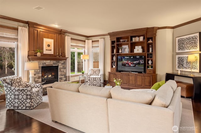 living area featuring visible vents, a fireplace, crown molding, and hardwood / wood-style floors
