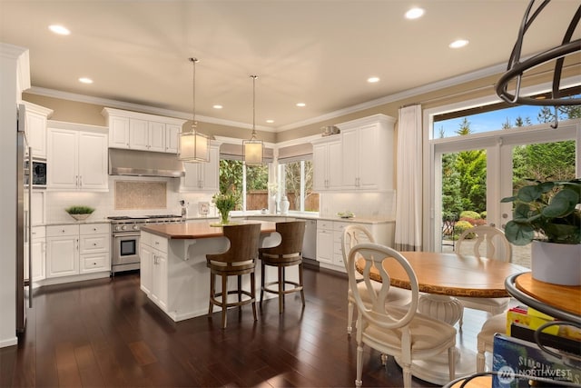 kitchen with a kitchen island, white cabinets, under cabinet range hood, high end stainless steel range, and crown molding