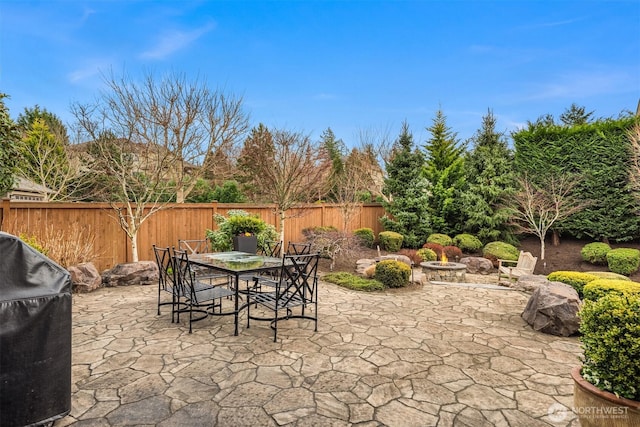 view of patio / terrace featuring a fenced backyard, grilling area, outdoor dining space, and an outdoor fire pit