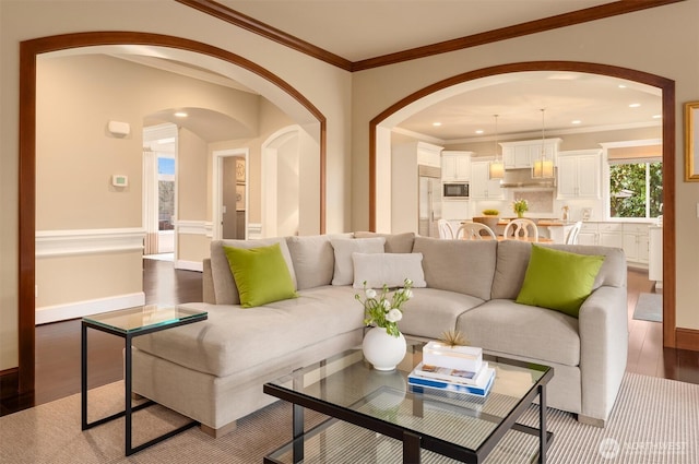 living area with wood finished floors, baseboards, recessed lighting, arched walkways, and ornamental molding