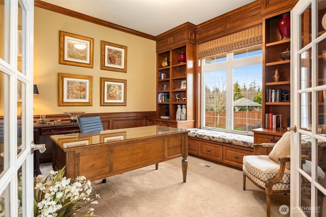 office space with light colored carpet, ornamental molding, wainscoting, and a decorative wall