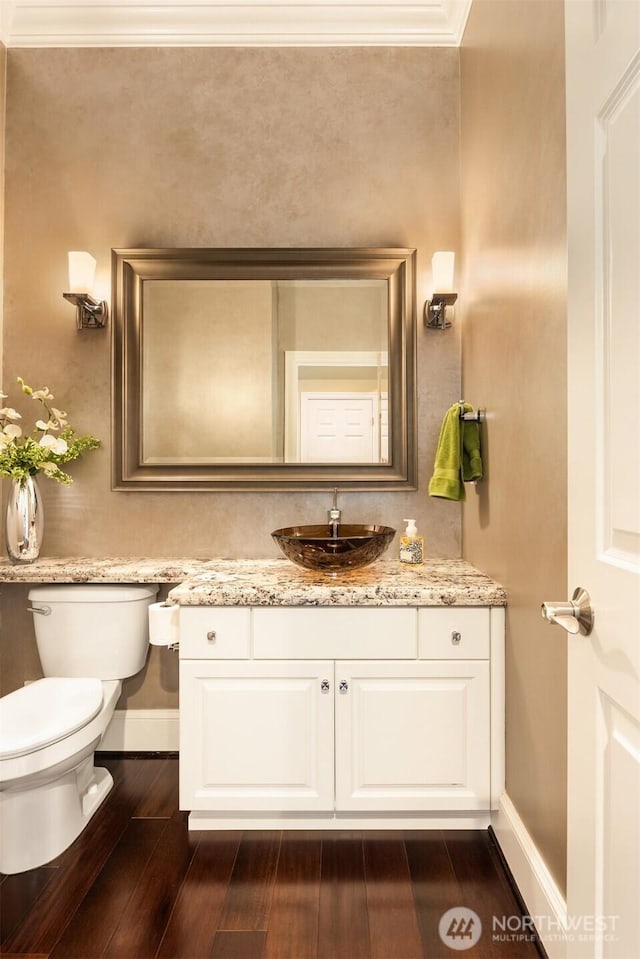 bathroom featuring crown molding, baseboards, toilet, wood finished floors, and vanity