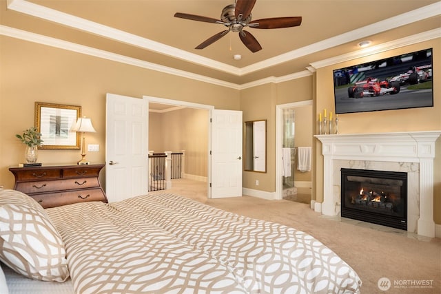 bedroom with carpet, baseboards, a premium fireplace, ensuite bathroom, and crown molding