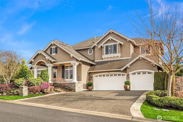 craftsman-style house with board and batten siding, a shingled roof, aphalt driveway, a garage, and stone siding