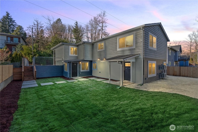 back of property featuring fence, central AC unit, and a lawn