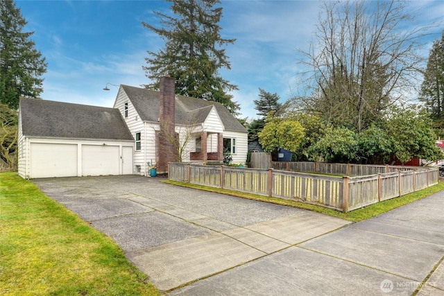 view of front of property featuring aphalt driveway, a fenced front yard, an attached garage, roof with shingles, and a chimney