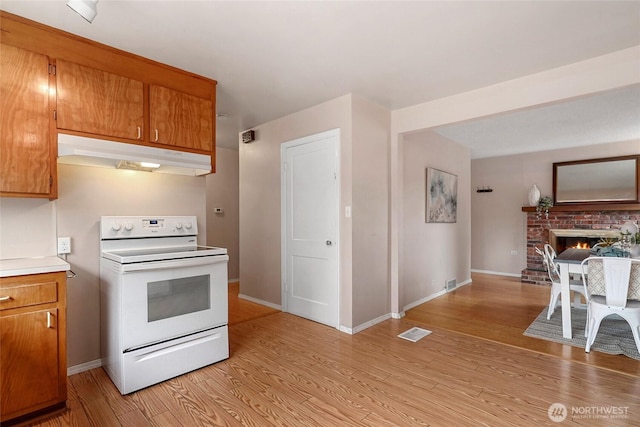 kitchen featuring brown cabinets, visible vents, under cabinet range hood, and white range with electric cooktop