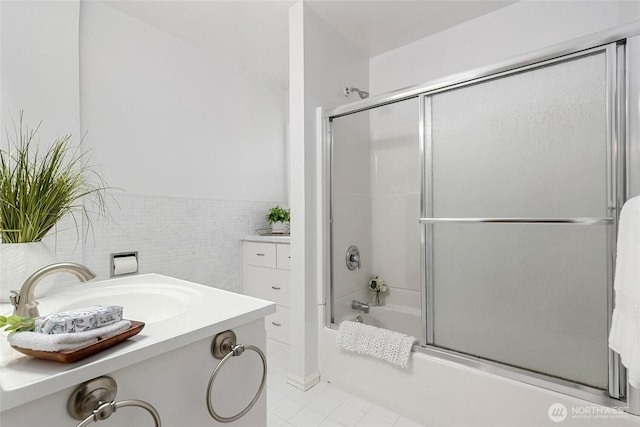 bathroom with shower / bath combination with glass door, tile patterned flooring, vanity, and tile walls