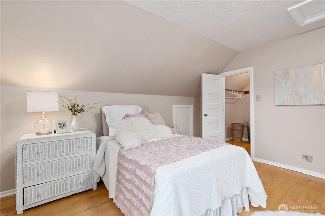 bedroom featuring attic access, baseboards, vaulted ceiling, and wood finished floors