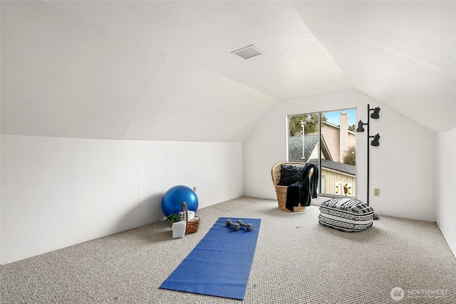 exercise area featuring carpet floors, visible vents, and vaulted ceiling