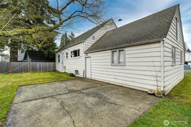 back of property featuring a patio area, a shingled roof, fence, and a lawn