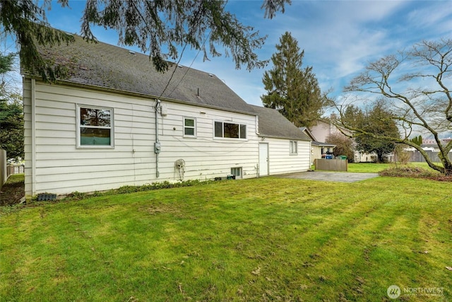 rear view of property featuring a yard, roof with shingles, and a patio area