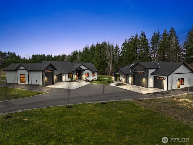 modern farmhouse featuring a front lawn, an attached garage, and driveway