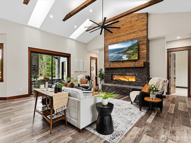 living area with baseboards, a fireplace, a skylight, wood finished floors, and high vaulted ceiling