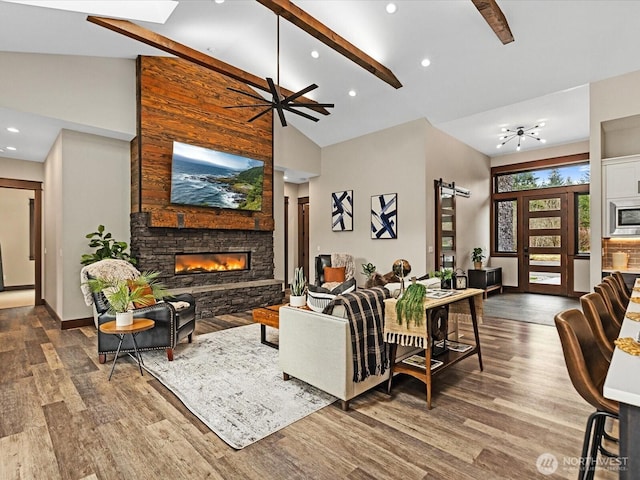 living room with a stone fireplace, high vaulted ceiling, a barn door, and wood finished floors