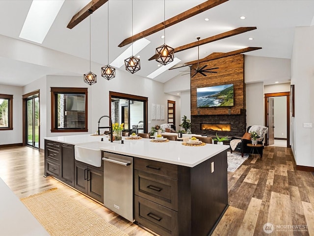 kitchen with open floor plan, light countertops, a fireplace, a skylight, and a sink