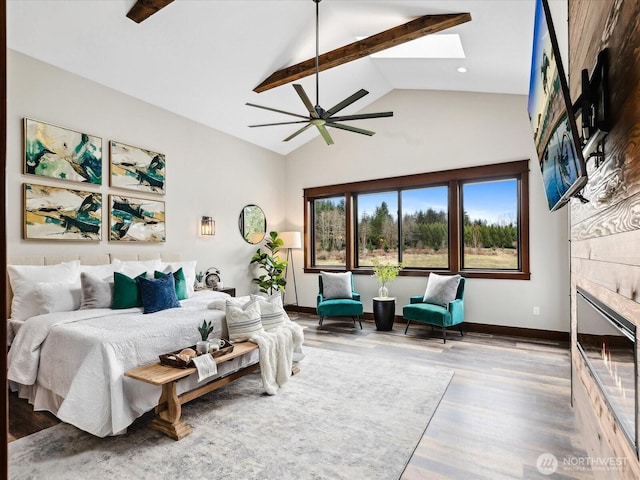 bedroom featuring baseboards, a tiled fireplace, beamed ceiling, a skylight, and wood finished floors