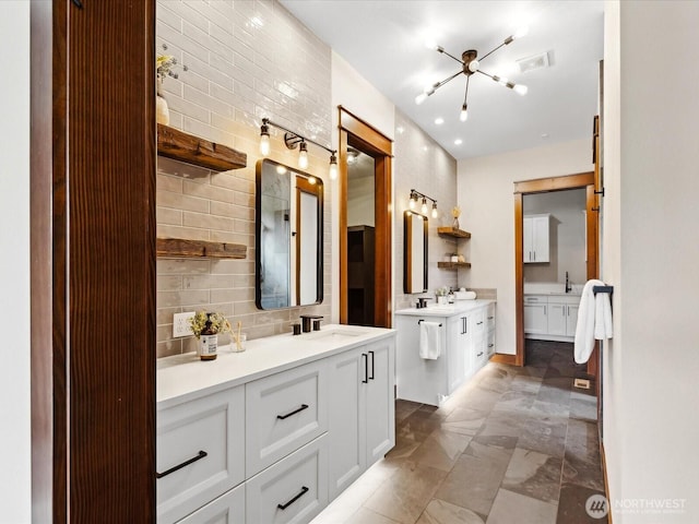 bathroom with two vanities, visible vents, backsplash, and a sink