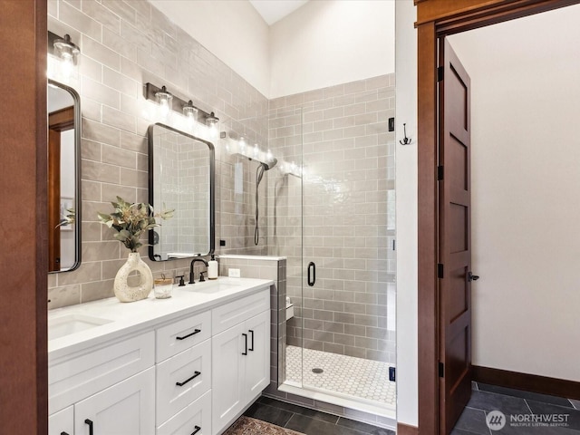 bathroom with tasteful backsplash, a shower stall, baseboards, double vanity, and a sink