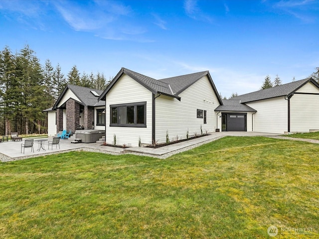 back of house with a hot tub, driveway, a yard, an attached garage, and a patio