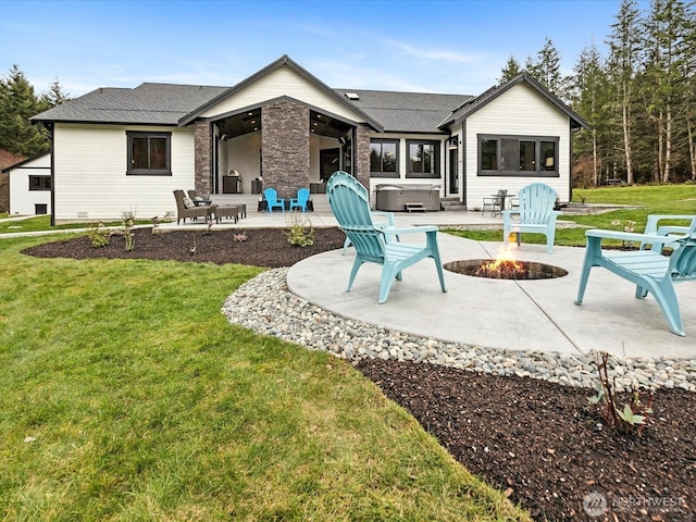 back of house with a patio area, a lawn, a fire pit, and a hot tub