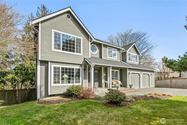 traditional-style house with a front lawn, covered porch, driveway, and fence