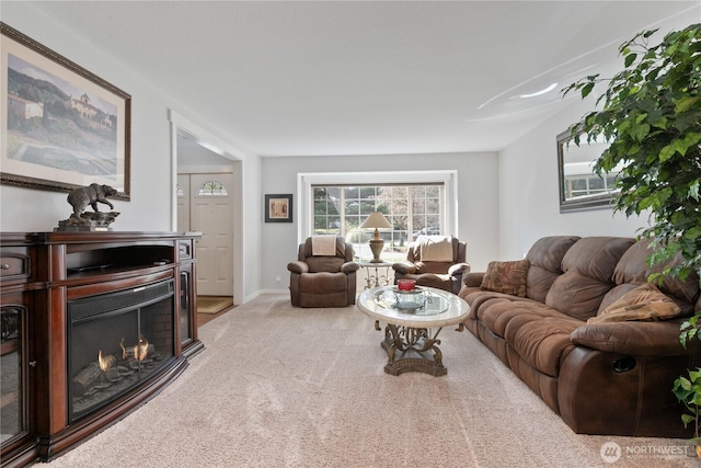 living room featuring baseboards, carpet floors, and a warm lit fireplace