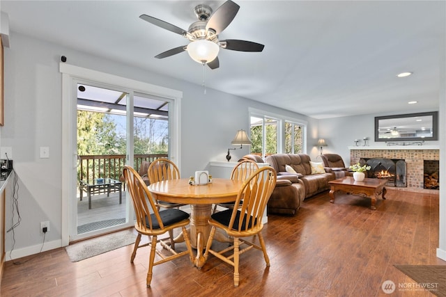 dining space with a ceiling fan, wood finished floors, recessed lighting, a fireplace, and baseboards