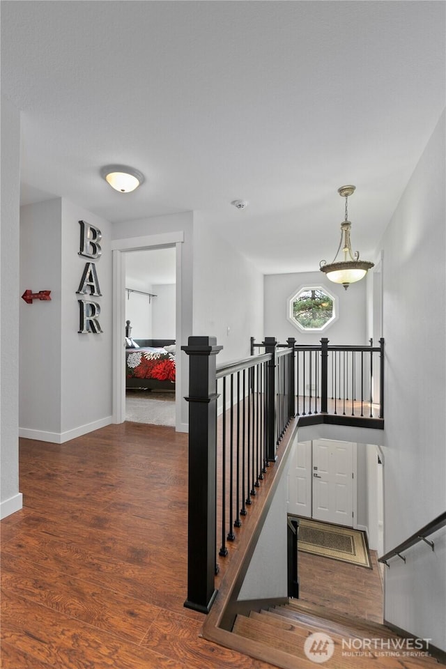 corridor featuring an upstairs landing, baseboards, and wood finished floors