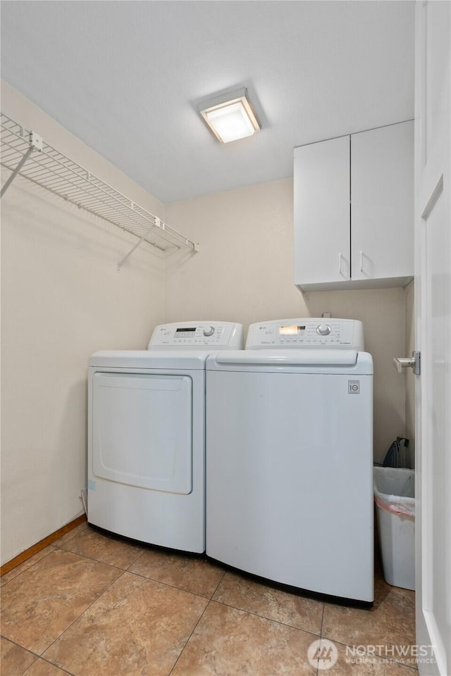 washroom with baseboards, cabinet space, and washing machine and clothes dryer